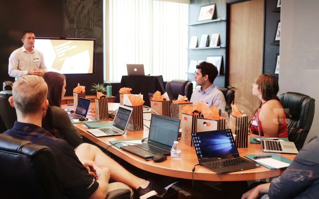 Präsentation vor einem Team mit Laptops als Situation beim Briefing schreiben und Besprechen