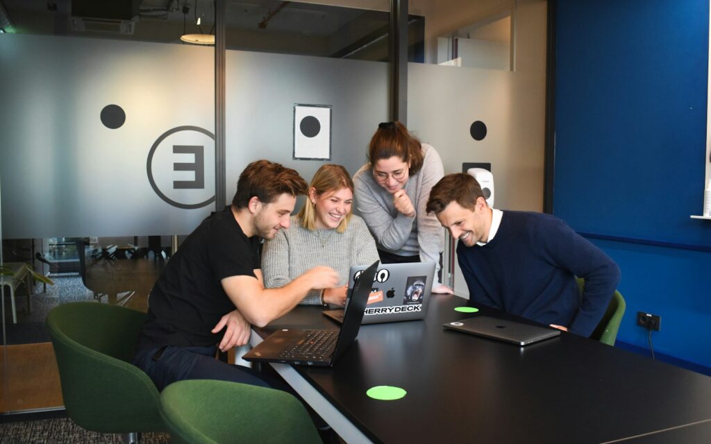 Team arbeitet gemeinsam an Laptops im Büro, Employer Branding durch gelebte Arbeitskultur