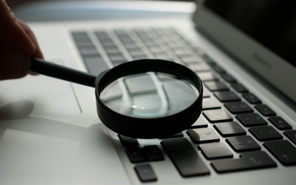 Lupe vor einem Laptop als Sinnbild für Meta-Title und Suchergebnisse