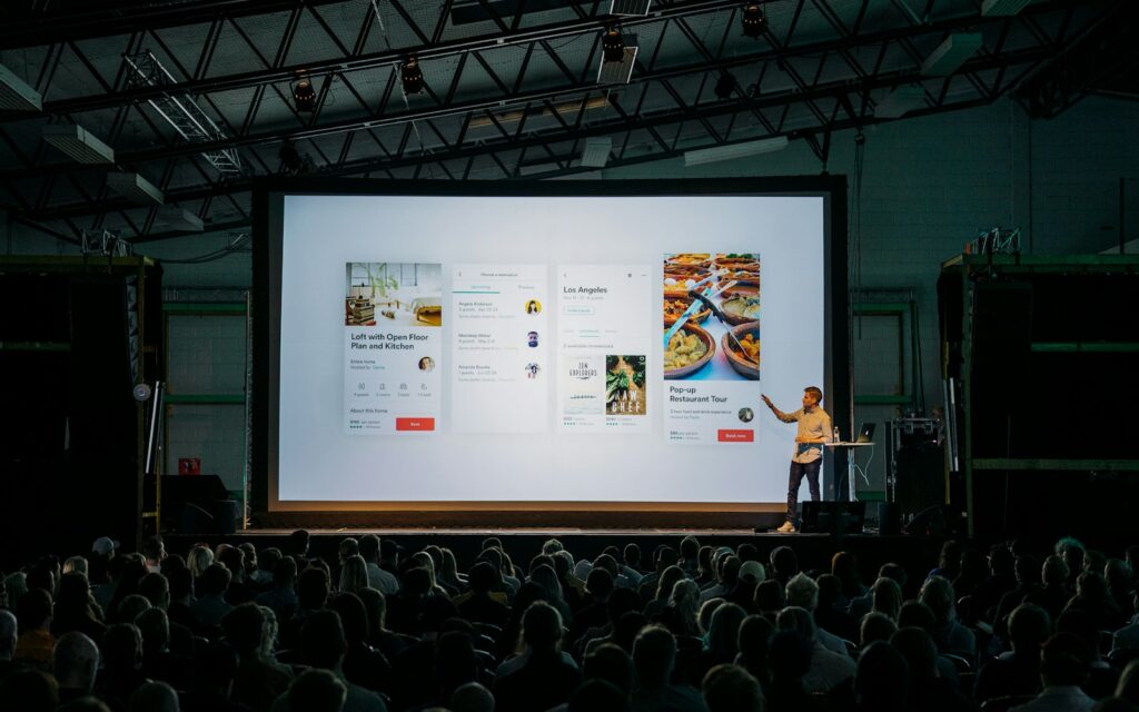 Präsentation vor großer Leinwand in abgedunkeltem Raum, wie bei einem Pitch-Deck-Termin