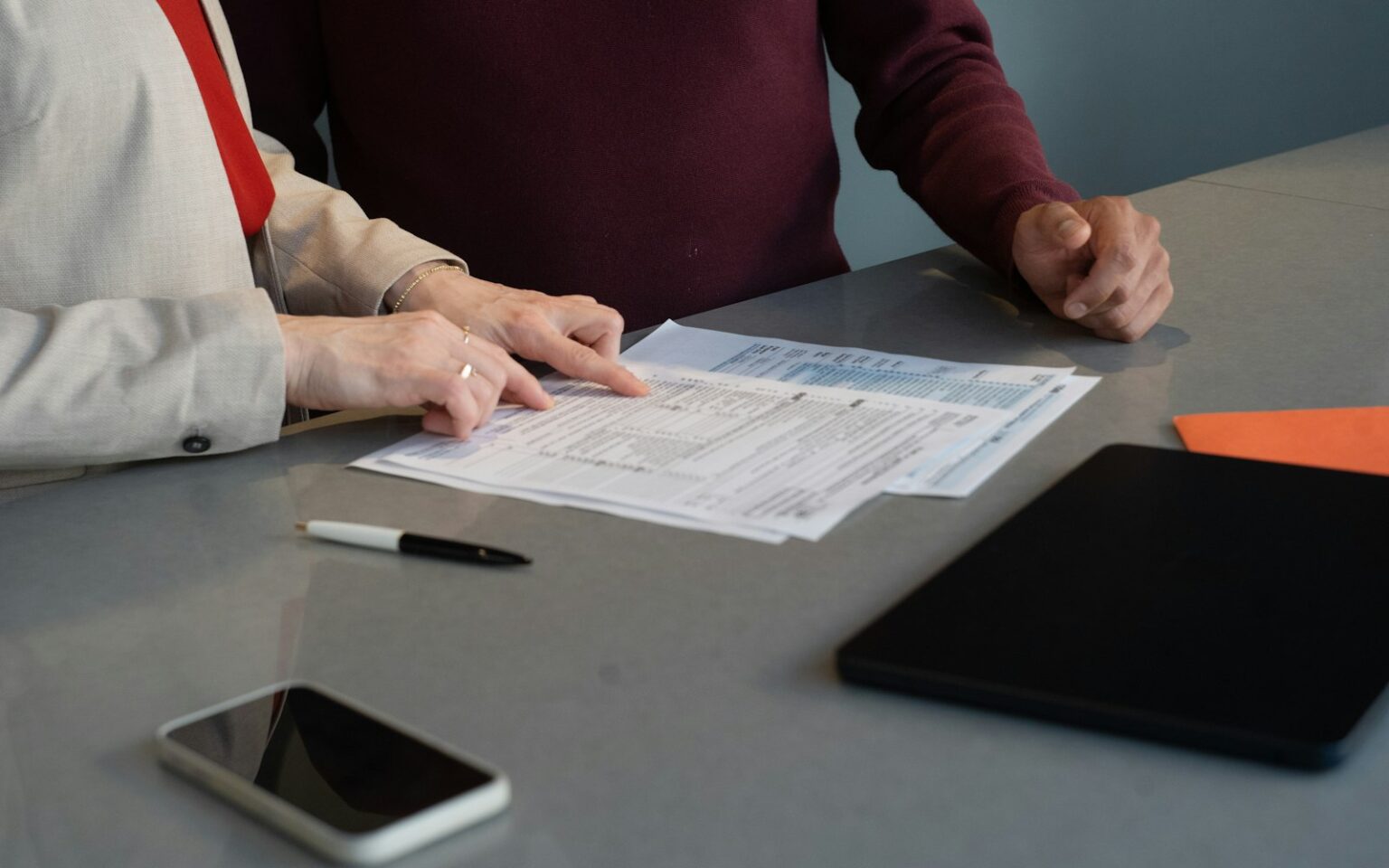 Zwei Personen prüfen am Tisch die Unterlagen für ihren Businessplan