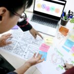 Designer entwirft am Schreibtisch Wireframes mit Call to Action Buttons