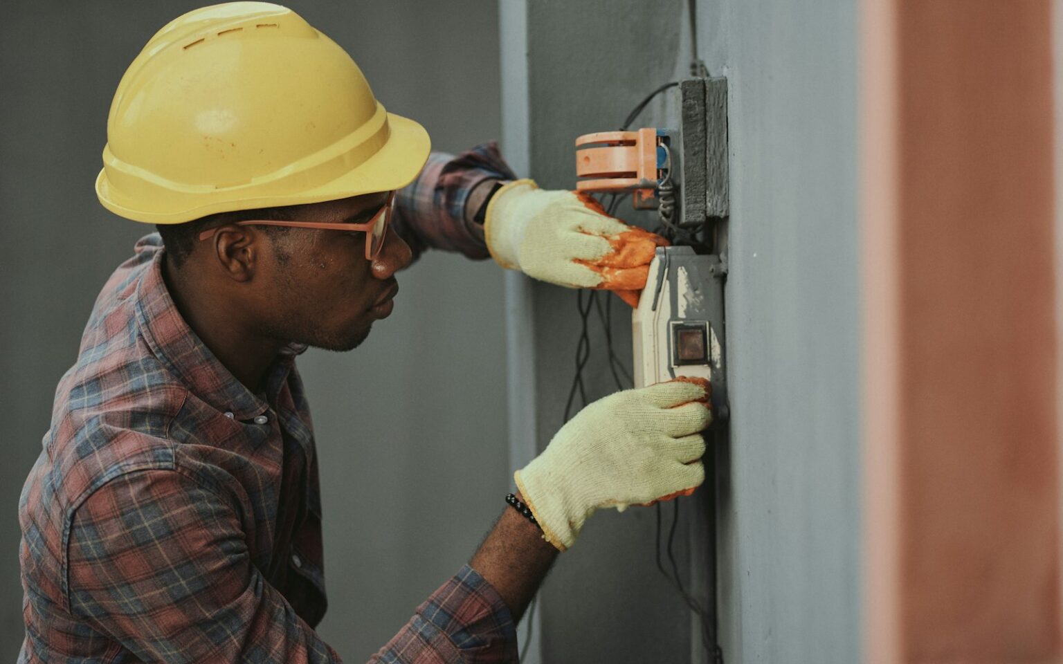 Elektriker mit Schutzhelm bei der Installation, dessen Aufträge ein CRM für Handwerker dokumentiert