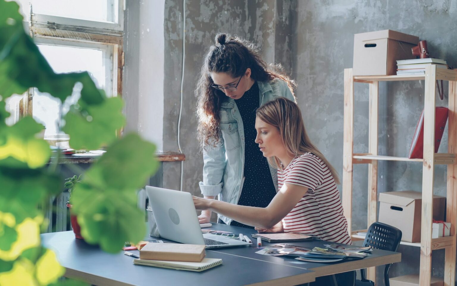 Zwei Kolleginnen besprechen am Laptop den Einsatz von KI-Tools für Unternehmen