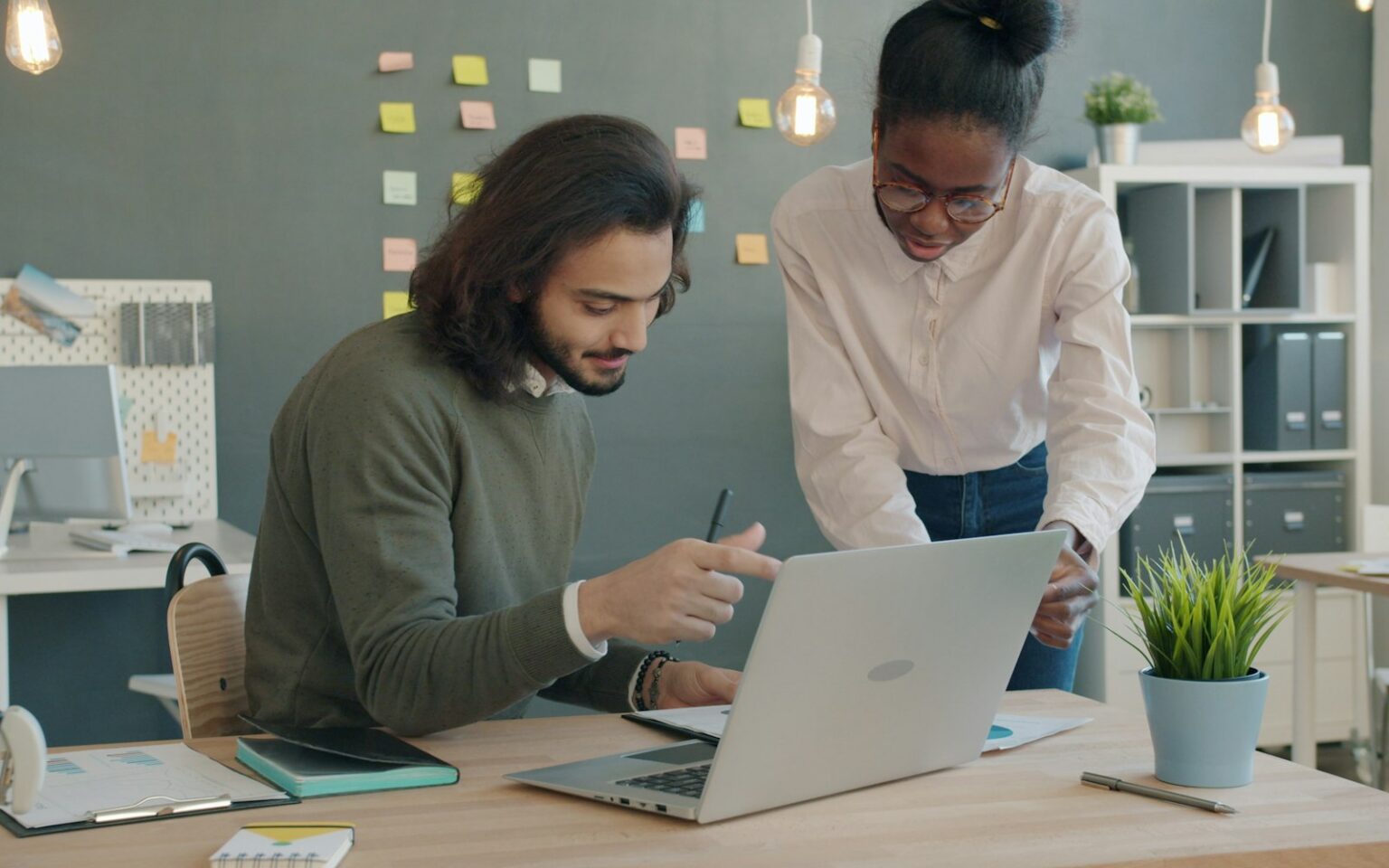 Zwei Kollegen planen Kundenakquise mit KI am Laptop im Büro