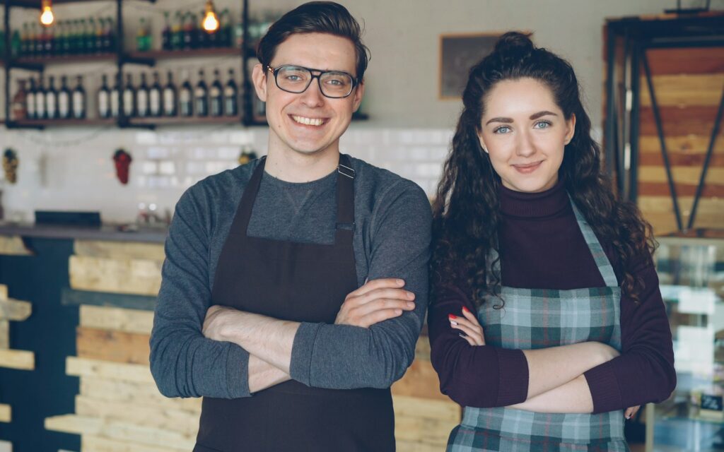 Zwei Cafébesitzer vor ihrem Laden, die Kundenbindungsmaßnahmen für Stammgäste planen