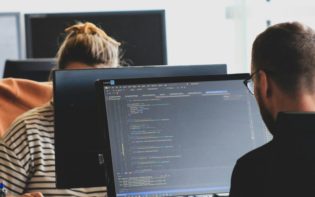 Zwei Personen prüfen am Monitor die llms.txt einer Unternehmenswebsite