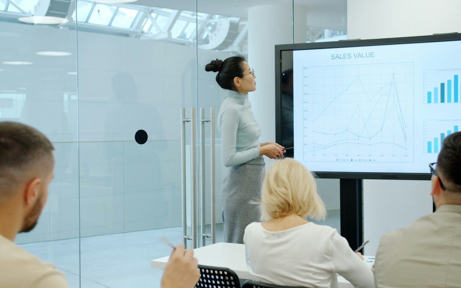 Marketerin präsentiert dem Team Kennzahlen zum Marketing Funnel auf einem Bildschirm