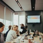 Gründerteam und Investoren sitzen an einem langen Tisch und verhandeln die Startup-Bewertung