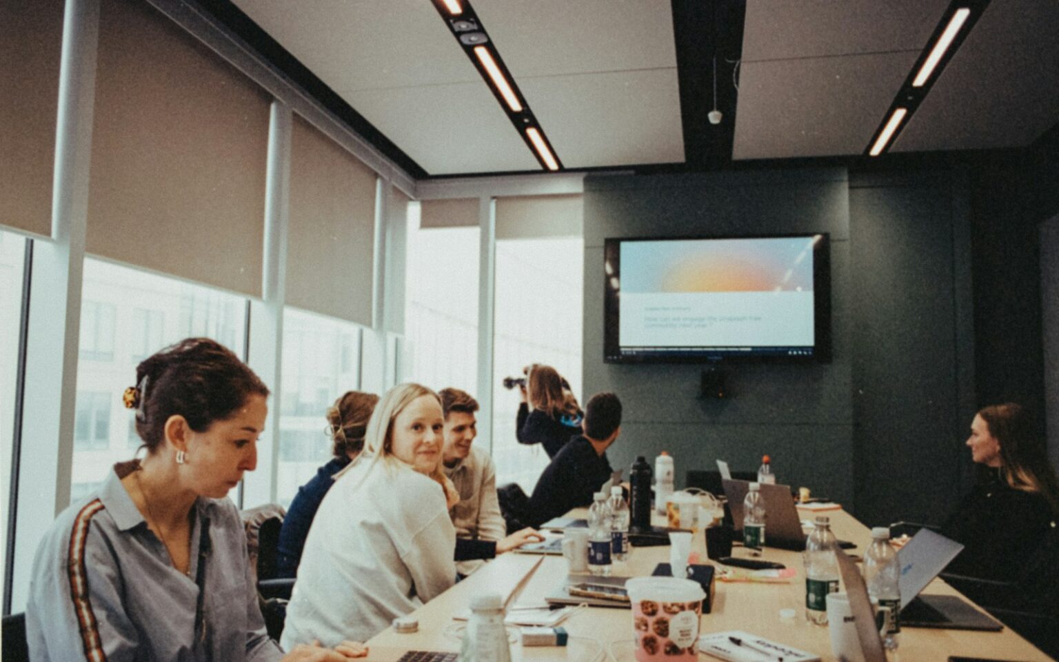 Gründerteam und Investoren sitzen an einem langen Tisch und verhandeln die Startup-Bewertung