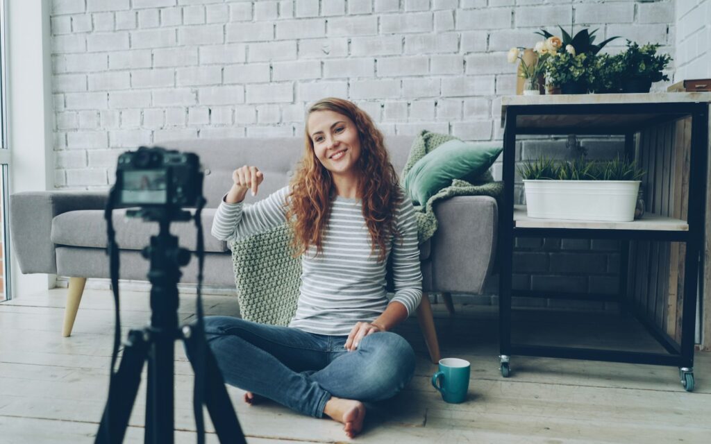 Frau nimmt zu Hause ein Video für TikTok-Trends auf und winkt in die Kamera