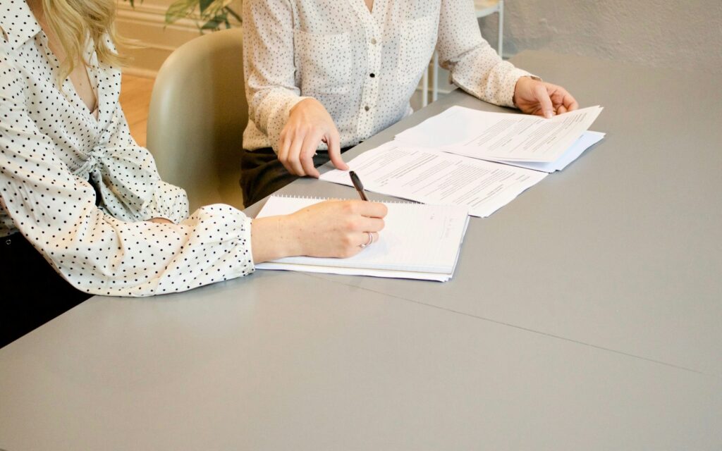 Gründerinnen unterschreiben Gründungsunterlagen nach der Entscheidung UG oder GmbH